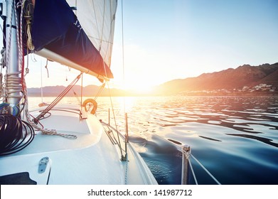 Sailing Yacht Boat On On Ocean Water At Sunrise With Flare And Outdoor Lifestyle