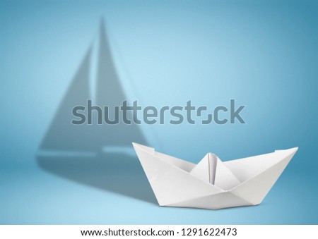 Sailing yacht concept, paper ship with sailing boat shadow on blue
