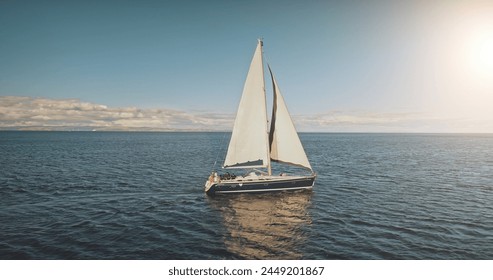 Sailing yacht race at sun light aerial. Yachting on serene seascape at open sea. Boat with big white spinnaker sail at ocean bay. Lonely ship cruise at water on summer sunny day. Cinematic drone shot - Powered by Shutterstock