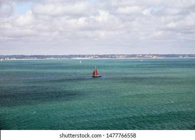 Sailing Yacht With Red Sail Goes On The Turquoise Sea, English Channel, United Kingdom