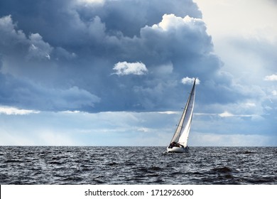 Sailing yacht regatta. Modern sailboat racing through the waves. Dramatic sky before the thunderstorm. Terrific cloudscape. North Germany, Kiel