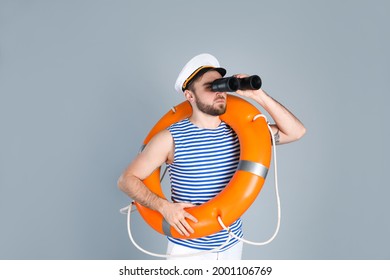 Sailor with binoculars and ring buoy on light grey background - Shutterstock ID 2001106769
