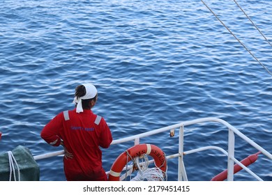 a sailor with a coverall and a headband is standing near the ship's railing and looking at the wide sea as if releasing heavy work. healing - Shutterstock ID 2179451415