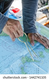 Sailor with divider in front of navigation chart of coastal area. Captain navigating sail boat ship