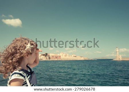 Sailor kid looking through the binoculars against blue sky background