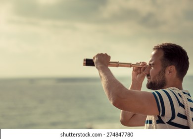 Sailor man looking through the binoculars against blue sky background