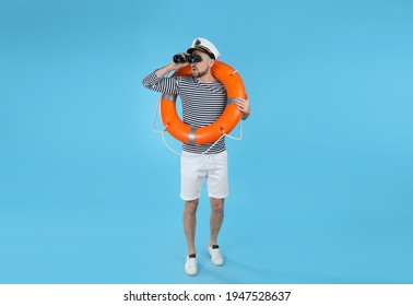 Sailor with orange ring buoy looking through binoculars on light blue background - Shutterstock ID 1947528637