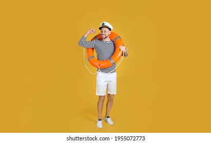Sailor with orange ring buoy showing biceps on yellow background - Shutterstock ID 1955072773