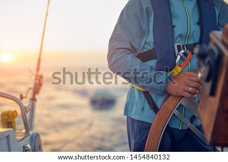 Sailor using wheel to steer rudder on a sailing boat.
