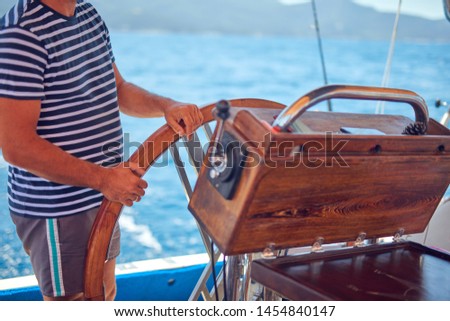 Sailor using wheel to steer rudder on a sailing boat.