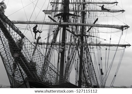 sailors working aloft in the rigging of a traditional tallship