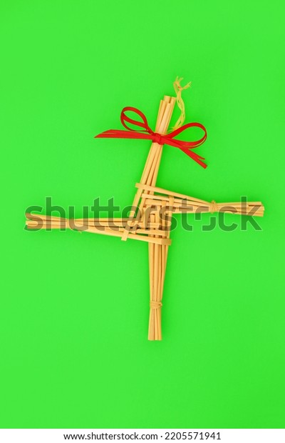Saint Brigids Cross Irish pagan symbol of house\
protection blessing against fire and evil. Traditionally made in\
Ireland on Imbolc first day of Spring on St Brigids feast day. On\
green, top view.