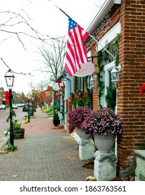 SAINT CHARLES, MISSOURI - November 23, 2020: A Small Business Storefront On Historic Main Street Decorated With Christmas Garland Flies An US Flag. The Historic District Is A Lewis And Clark Site.