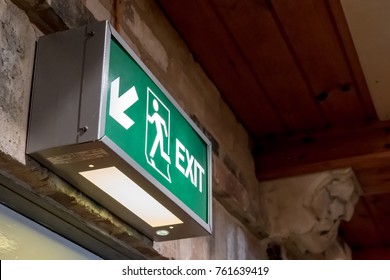 Saint Ives, Cambridgeshire, UK - Circa November 2017: Detailed View Of An Illuminated Emergency Exit Sign Seen Above An Interior Doorway, Located Within A Church, Required By Health And Safety.