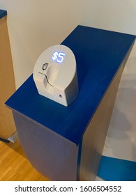 Saint Louis, MO—Jan 4, 2019; A White Plastic Dip Jar Credit Card Tip Device With A Glowing Five Dollar Sign Sits On A Blue Shelf At The St Louis Aquarium To Accept Donations