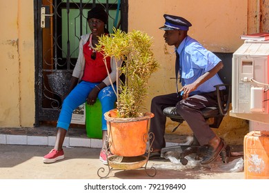 SAINT LOUIS, SENEGAL - APR 24, 2017: Unidentified Senegalese man in uniform and woman sit near the plant on the street of Saint Louis, one of the biggest cities in Senegal - Shutterstock ID 792198490