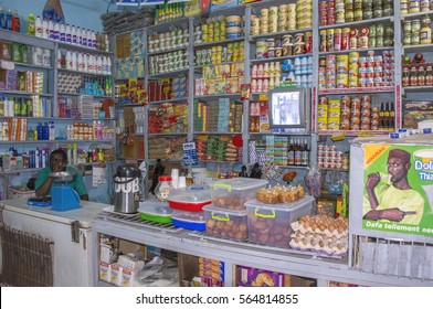 SAINT LOUIS, SENEGAL - MAY 28, 2014: Typical Grocery Store, Open At Night, Full Of Shelves With Products And An Employee Sitting In A Corner