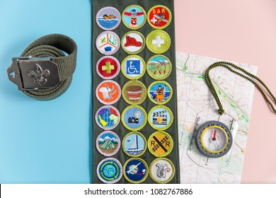 SAINT LOUIS, UNITED STATES - MAY 3, 2018:  Boy Scouts Of America (BSA) Merit Badge Sash, Belt, Compass, And Map On Pink And Blue Background As BSA Welcomes Girls To Join Scouting