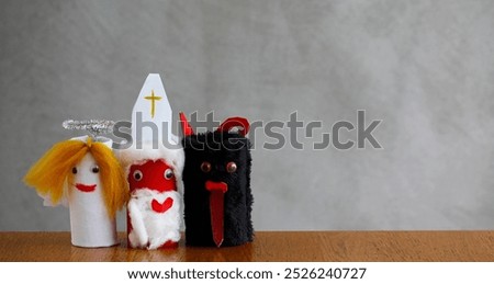 Saint Nicholas, Angel and Devil made by a child from toilet paper roll tubes. Saint Nicholas, Angel and Devil on gray background. Simple diy creative Christmas idea. Eco-friendly recycle decoration.