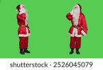 Saint nick having fun with music, listening songs on headphones and dancing in red festive suit. Young man enjoying christmas eve celebration, using audio headset on greenscreen.