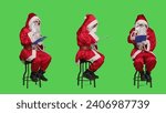 Saint nick writing notes on clipboard while he sits on chair dressed in red costume and white beard, full body greenscreen. Father christmas character holding papers in studio.