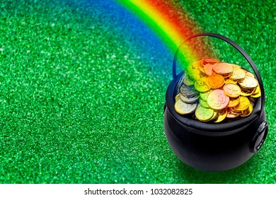 Saint Patrick's Day And Leprechaun's Pot Of Gold Coins Concept With A Rainbow Indicating Where The Leprechaun Hid Treasure On Green With Copy Space. St Patrick Is The Patron Saint Of Ireland