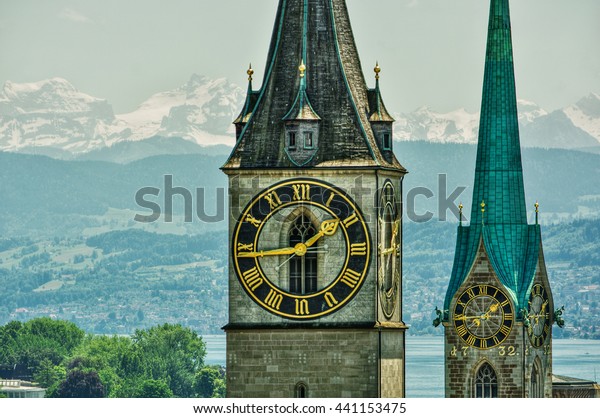 Saint Peter\
and FraumÃ¼nster Church in Zurich (Switzerland) in front of lake\
Zurich and the Swiss Alps,\
HDR-technique