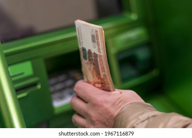 Saint Petersburg, Russia, 04.30.2021, An Elderly Woman Holds 5,000 Rubles In Her Hand Near An ATM. Cash Withdrawal, Loan Repayment