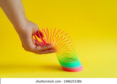 Saint Petersburg, Russia, 21 August 2019 -hands stretched plastic  rainbow spiral on a yellow background