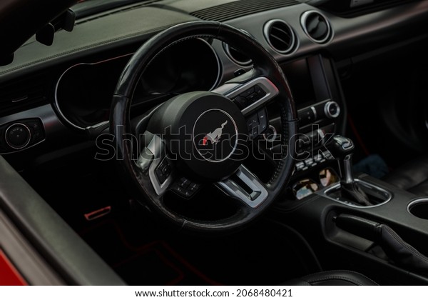 Saint PETERSBURG, Russia - August 10,\
2021: MUSTANG car emblem and brand logo. Sports steering wheel and\
car interior. A modern and high-tech car built by one of the famous\
American car\
manufacturers.