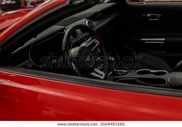 Saint PETERSBURG, Russia - August 10,\
2021: MUSTANG car emblem and brand logo. Sports steering wheel and\
car interior. A modern and high-tech car built by one of the famous\
American car\
manufacturers.