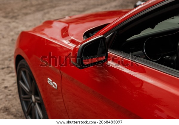 Saint PETERSBURG, Russia -\
August 10, 2021: Red FORD MUSTANG Car. Side mirror. A modern and\
high-tech car built by one of the famous American car\
manufacturers.