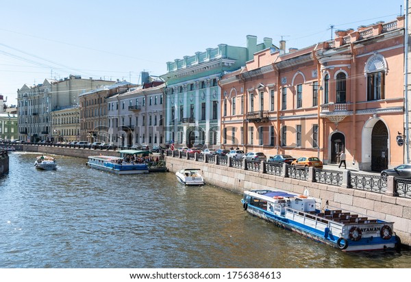 Saint Petersburg,\
Russia – June 15, 2017. View of Moyka River and embankment in Saint\
Petersburg, with historic buildings, commercial properties, boats,\
cars and people. 