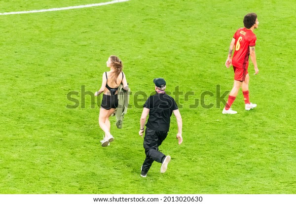 Saint Petersburg, Russia – June 21, 2021. Security\
officer chasing a female pitch invader during EURO 2020 match\
Finland vs Belgium (0-2).