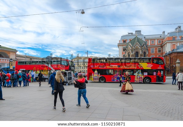 SAINT PETERSBURG, RUSSIA - MAY 1,\
2017: Group of unknown tourists is by excursion buses near\
chapel-sacristy of Iberian Icon of Mother of God (Stone\
Museum)