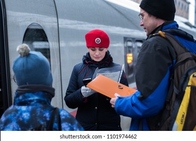 Saint Petersburg, Russia - October 29, 2017: A Train Conductor In A Red Beret Of A Sapsan Express Train Checks In A Passenger With A Child Using Electronic Device At Moskovsky Railway Station.