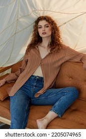 Saint Petersburg Russia - September, 5 2022: Pretty Curly Haired Model Posing On A Orange Couch In The Studio.