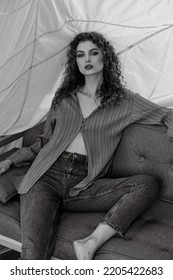 Saint Petersburg Russia - September, 5 2022: Pretty Curly Haired Model Posing On An Orange Couch In The Studio.