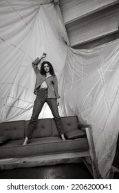 Saint Petersburg Russia - September, 5 2022: Feminine Caucasian Woman Posing Full Height On The Orange Couch In Front Of The Parachute In The Studio. Black And White Photo.