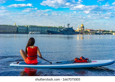 Saint Petersburg. Russia. SUP surfing. Girl sitting on an inflatable Board. Riding on an inflatable Board on the Neva river. Palace embankment. Hermitage. Ships. Isaakievsky cathedral.