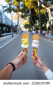 Saint Stephen, Montenegro, 07.07.2021: Beautiful Bright Ice Cream With Different Flavors In The Hands Of A Young Couple In Love. Selective Focus, Noise. Beautiful City Streets. Leisure Concept