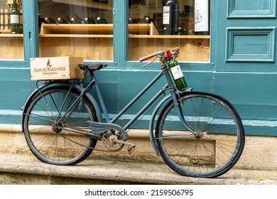 Saint-Emilion, France - 10 May, 2022: Old Bicycle With Basket And Wine Bottle Parked Outside A Wine Shop In The Quaint Village Of Saint-Emilion