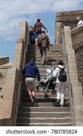 SAINT-MALO, FRANCE - JULY 6, 2011: People Climbing Steps In Old Town Of Saint-Malo. Parents Are Carrying A Baby Stroller With Their Child Upstairs.