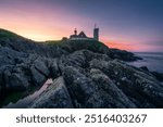 Saint-Mathieu Lighthouse at sunrise, with cliff rocks on foreground, on Pointe Saint-Mathieu in Plougonvelin, Brest, France