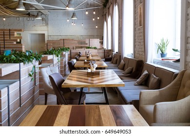 Saint-Petersburg, Creative Space Tkachi, May 2017. Wooden White Bricks Wall Loft Interior Cafe, Coffee Shop, Coworking Area. Tables, Chairs, Plants And Retro Lights