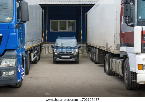 Saint-Petersburg,\
Russia - April 29th, 2019: Light commercial vehicle Citroen\
Berlingo (Peugeot Partner) between two semi-trailer trucks. Small\
transport business growth\
concept.
