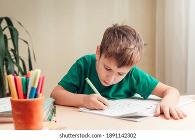 SAINT-PETERSBURG, RUSSIA - DECEMBER 18, 2020 Cute 7 years old child doing his homework sitting by desk. Boy writing in notebook.