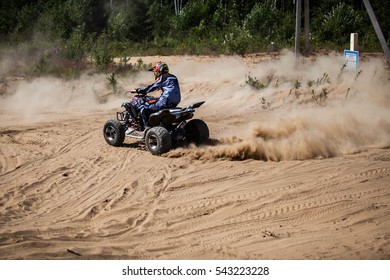 SAINT-PETERSBURG, RUSSIA - JULY 2014: unknown man riding in the wood on a ATV Yamaha Raptor R700. He ride in the sand and dust flies under the wheels. Dressed in a suit and helmet Fox Head.
