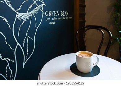 Saint-Petersburg, Russia - May 25, 2021: Starbucks Coffee Cup On A Cafe Table And Noisy Street Behind Window