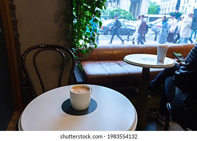 Saint-Petersburg, Russia - May 25, 2021: Starbucks Coffee Cup On A Cafe Table And Noisy Street Behind Window